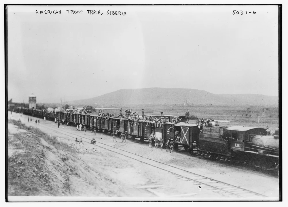 Historical black-and-white photograph of a train and wagons in Siberia, used illustratively